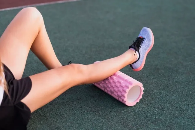 6 Fascial Fitness Training Principles to Boot Mobility, Strength & Recovery - A woman using a foam roller to stretch her legs.